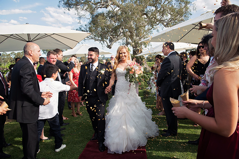 Couple walking down the aisle at McLarenvale Old Oval Estate with guests throwing petal confetti, Happy couple just married wedding photography