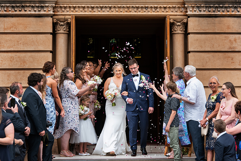 Couple walking down the aisle at Sacred Heart church  Adelaide with guests throwing petal confetti, Happy couple just married wedding photography